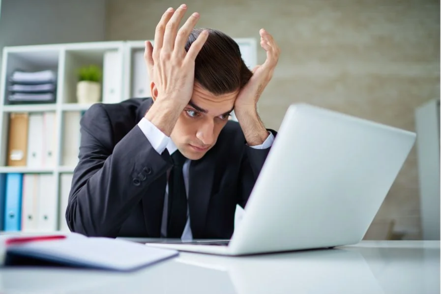 Business professional stressed while reviewing financial work on a laptop